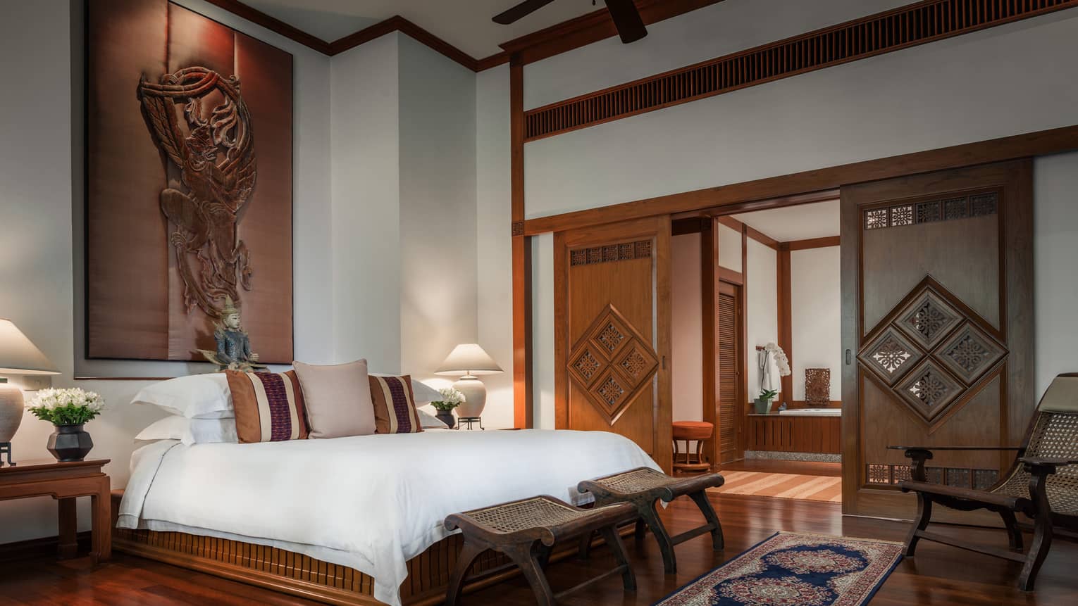 Penthouse Residence bedroom with high ceilings, wood sculpture over bed, sliding wood doors 