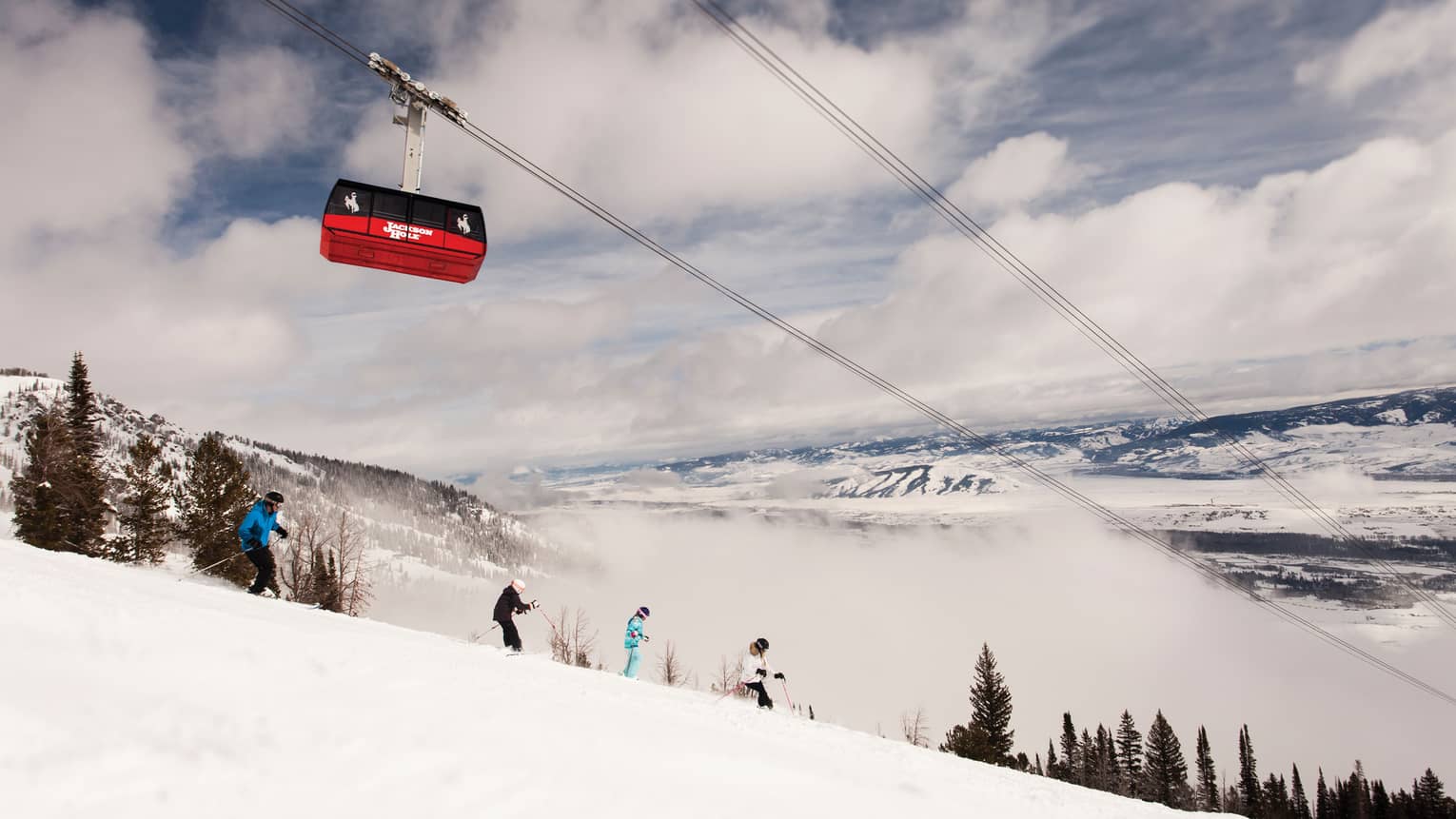 Red Sweetwater Gondola ski lift on wire above hikers on snowy mountain