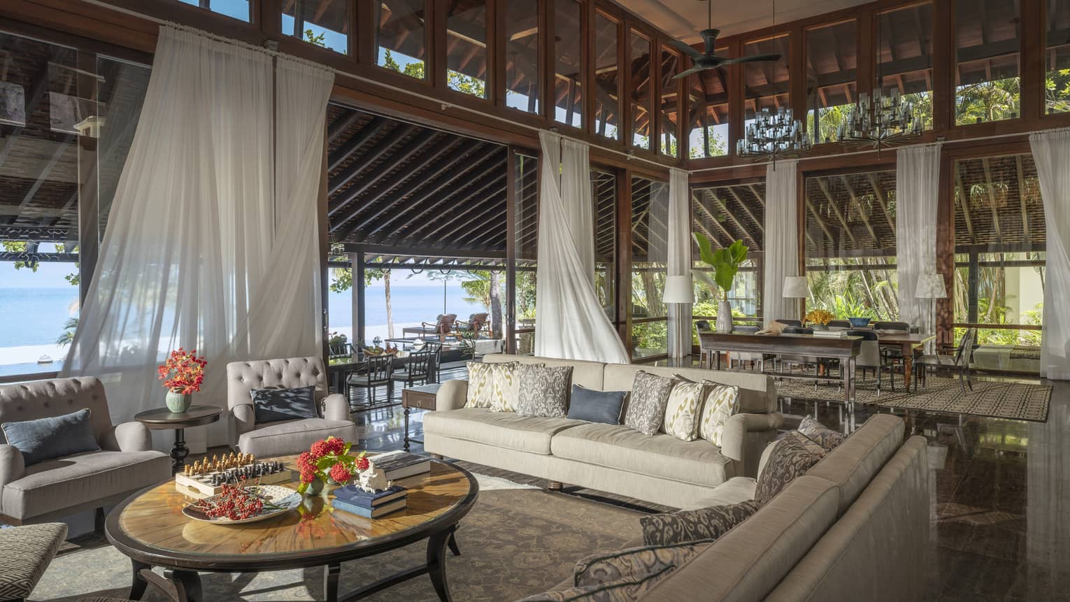 Vast indoor-outdoor living room and great room with high ceilings, flowing white curtains, beach view