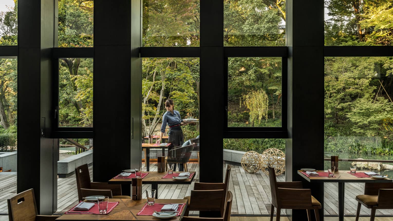 View of Brasserie patio and forest through window, server sets table