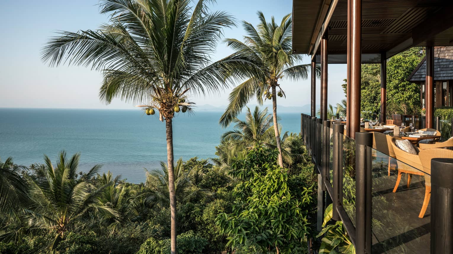Corner patio dining room with glass balcony, high up on tropical mountain overlooking ocean