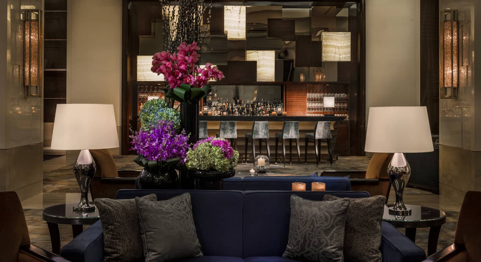 Opus Bar with grey stools behind lounge sofas, purple flowers