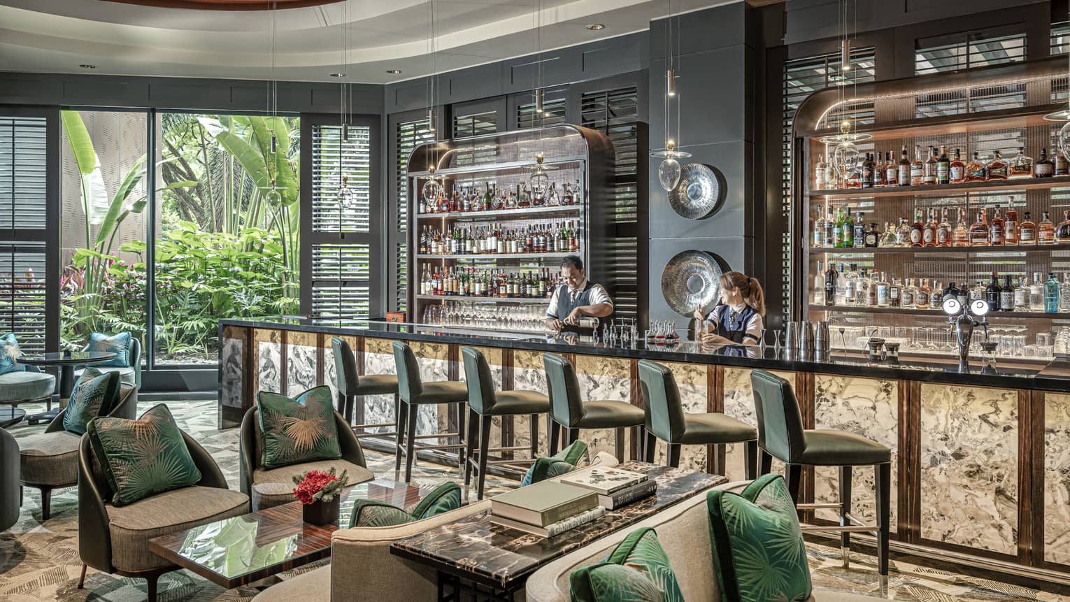 Male and female bartender stand behind counter at light-filled One-Ninety Bar