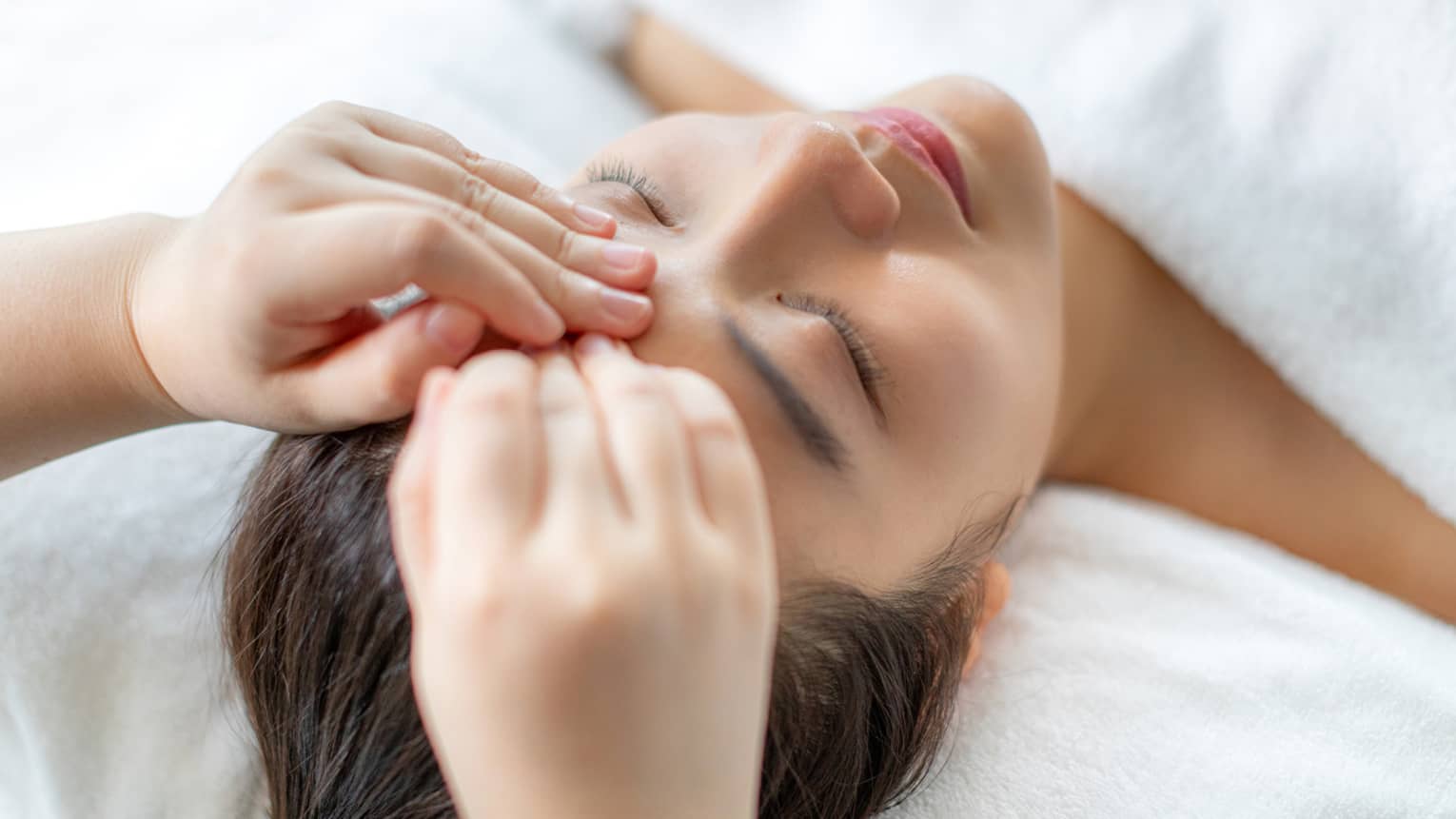 A woman getting a facial massage in a spa.