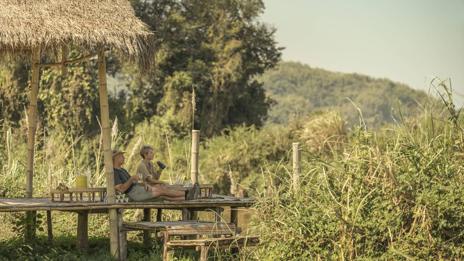 Couple enjoys a camp picnic with views of Thailand's rolling green hills