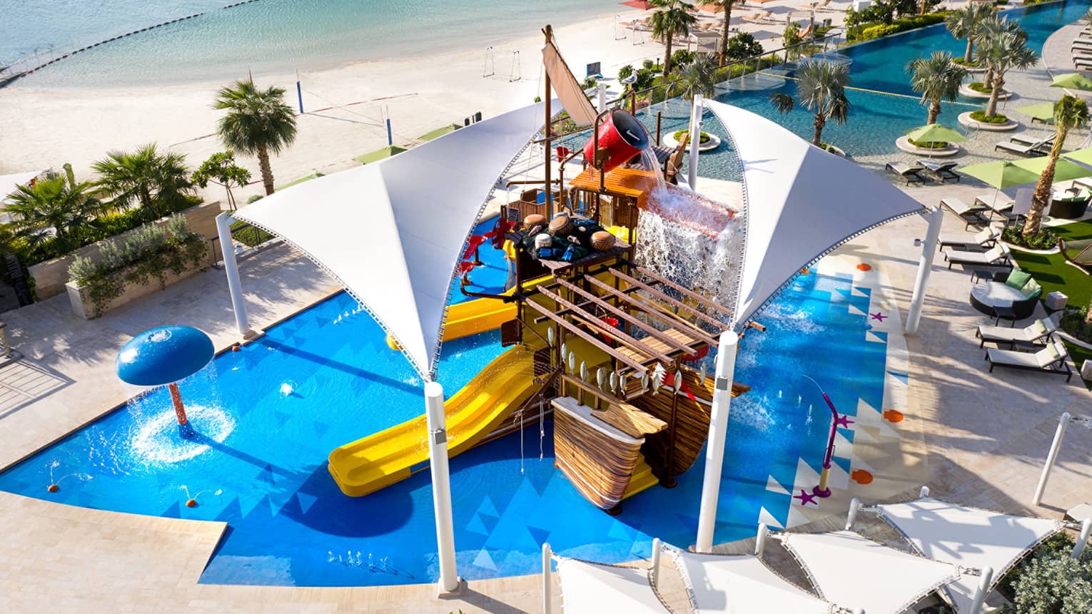 A large orange waterslide built into a faux pirate ship descending into a crystal blue pool of water.