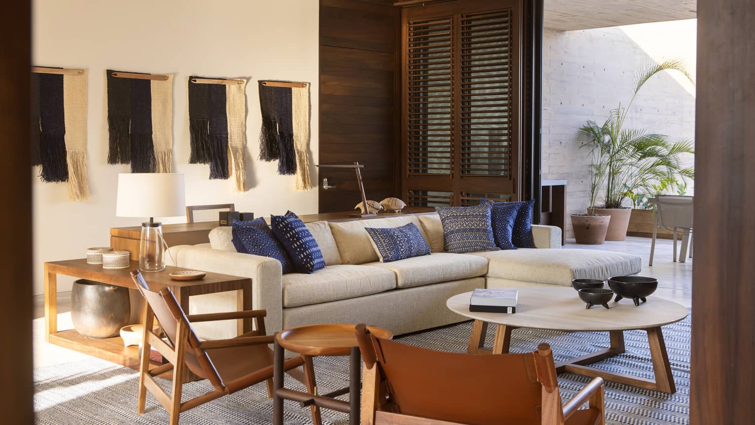 Suite living area with cream couch and blue accent pillows, twin folding chairs, round coffee table, door to outdoor space with potted plant