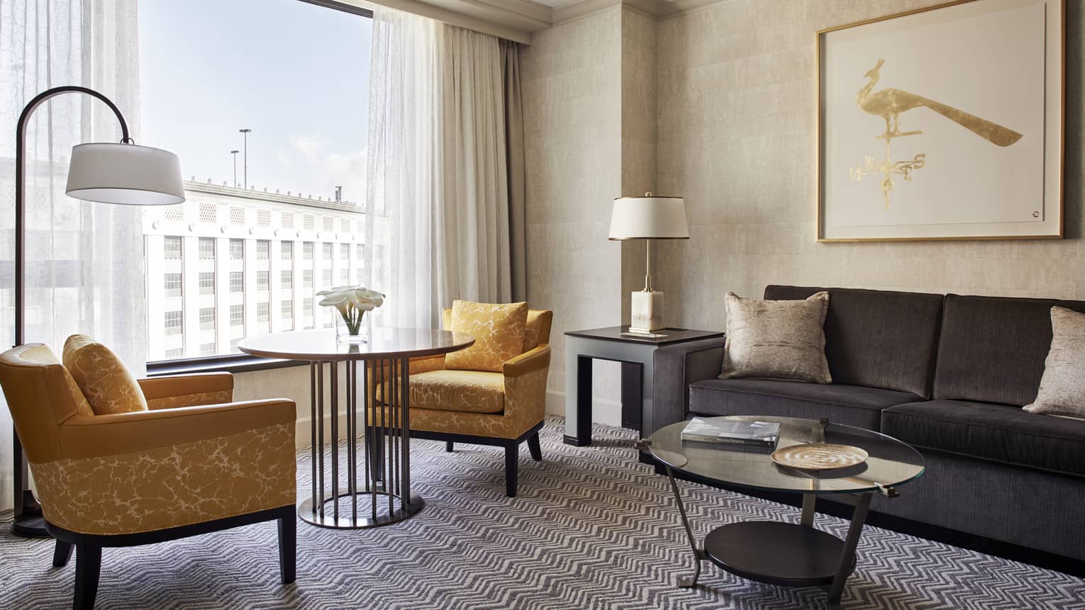 Superior Room living area with two yellow fabric armchairs around round cafe table in front of window, grey sofa