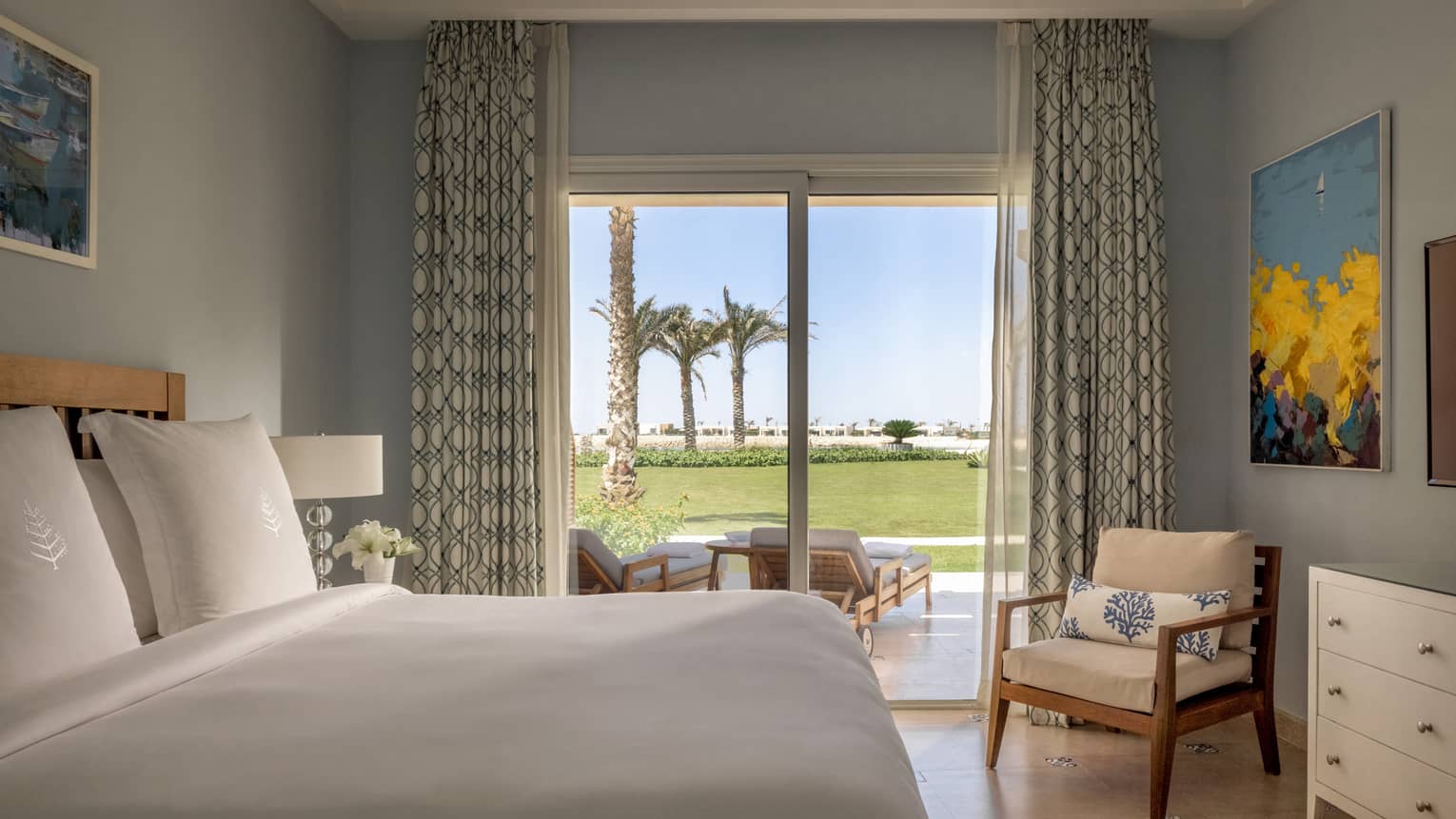Guest bedroom with king bed, armchair, sliding glass door to terrace