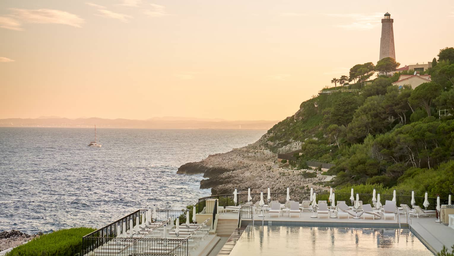 Club Dauphin pool, sea and lighthouse view at sunset