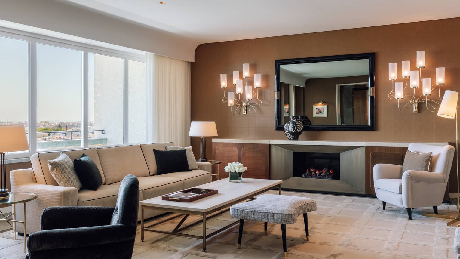 Living room with cream sofa, white arm chair, black arm chair, wall schones, brown accent wall