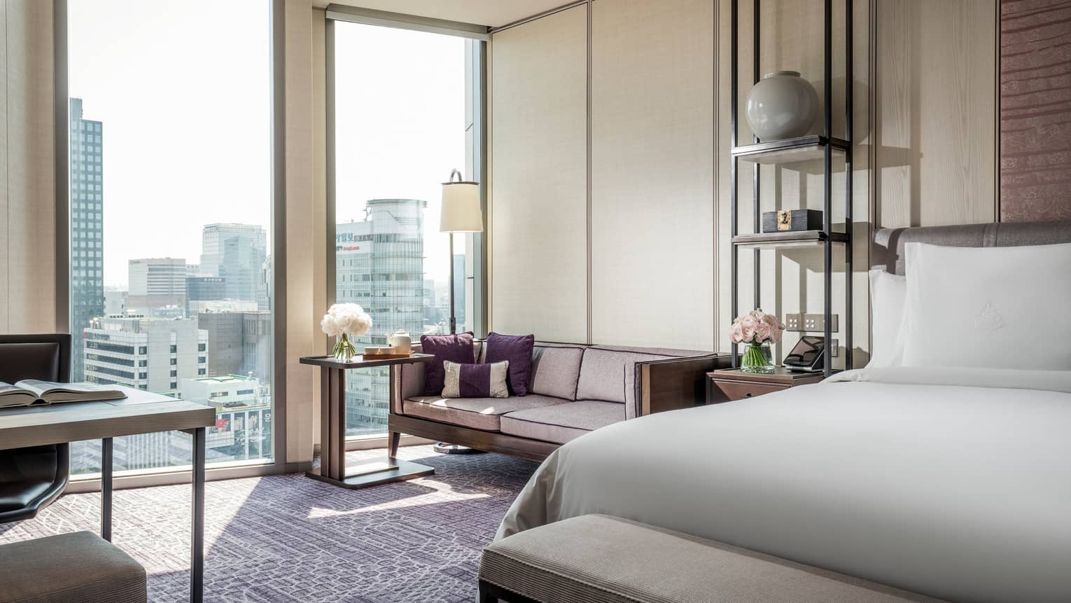 Premier Room bed with bench at foot, small sofa and table, flowers by large sunny windows, work desk
