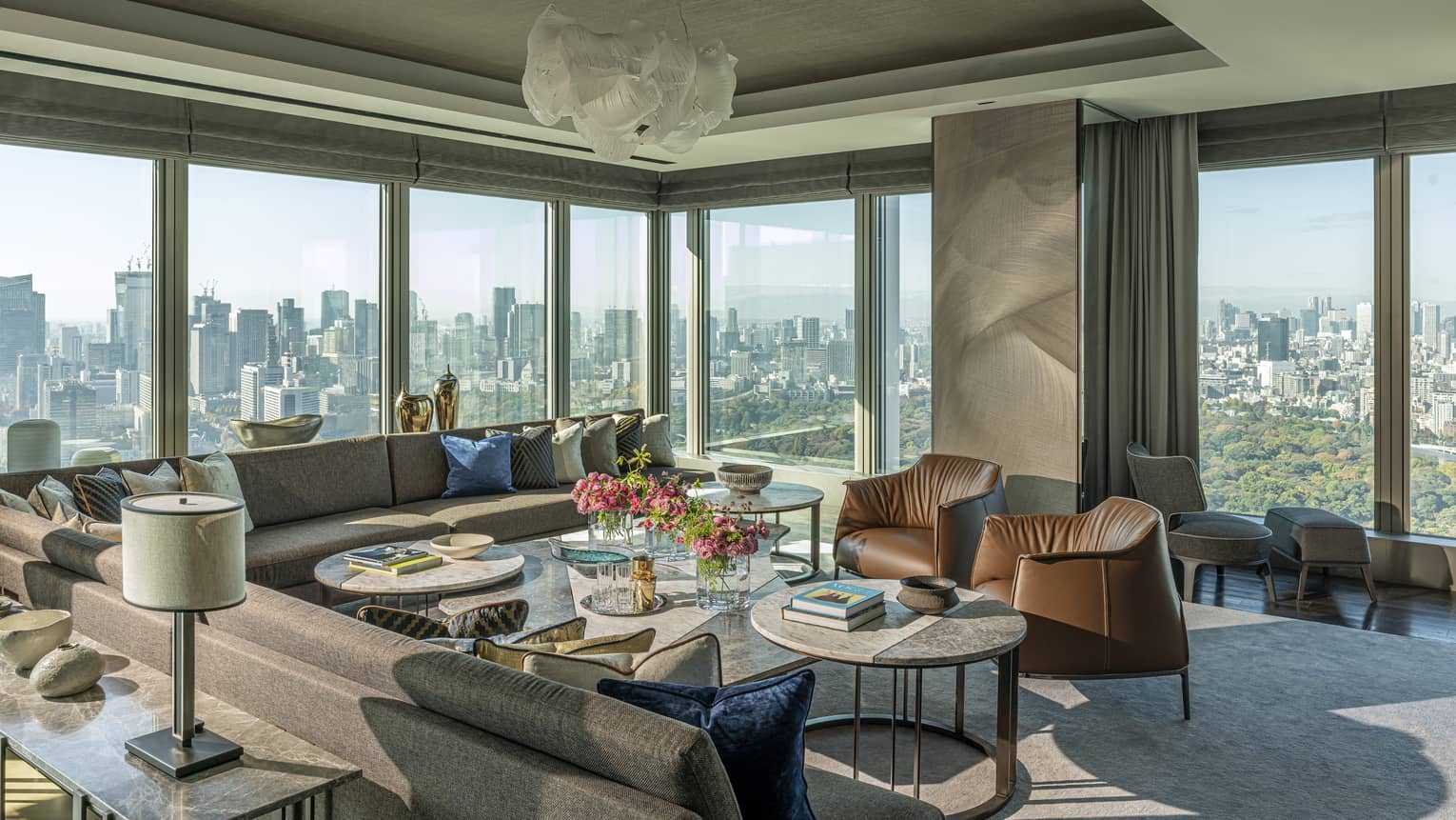 Elegant living room with large sectional sofa, two chairs, walls of windows, chandelier