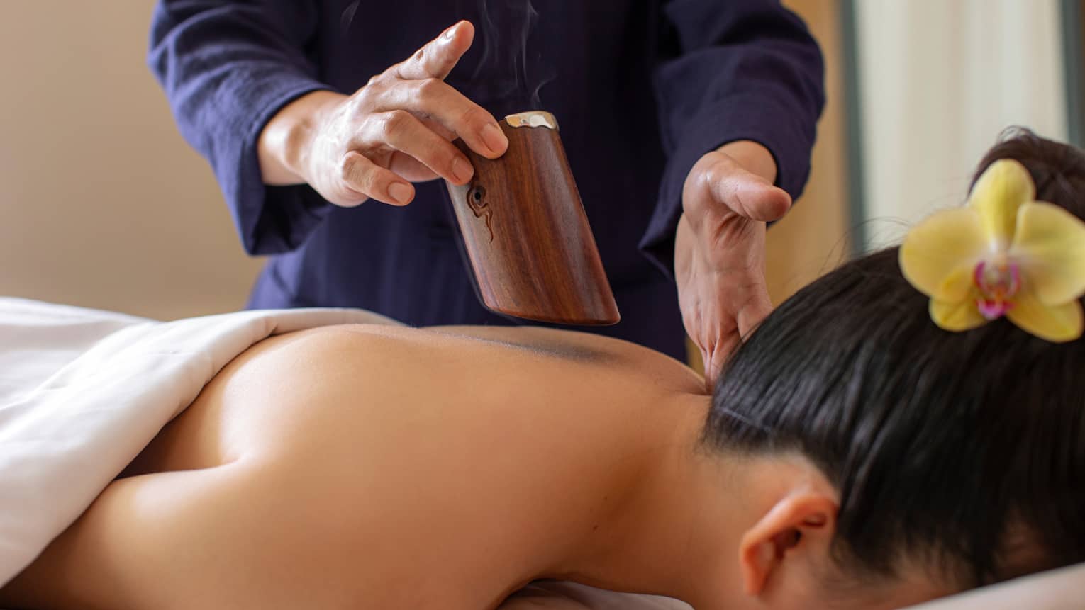 Spa therapist performs reed wood moxibustion on female guest