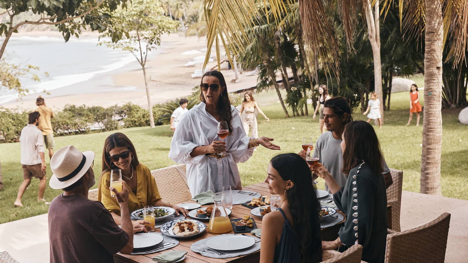 Friends and family enjoying a meal and kids playing in the background