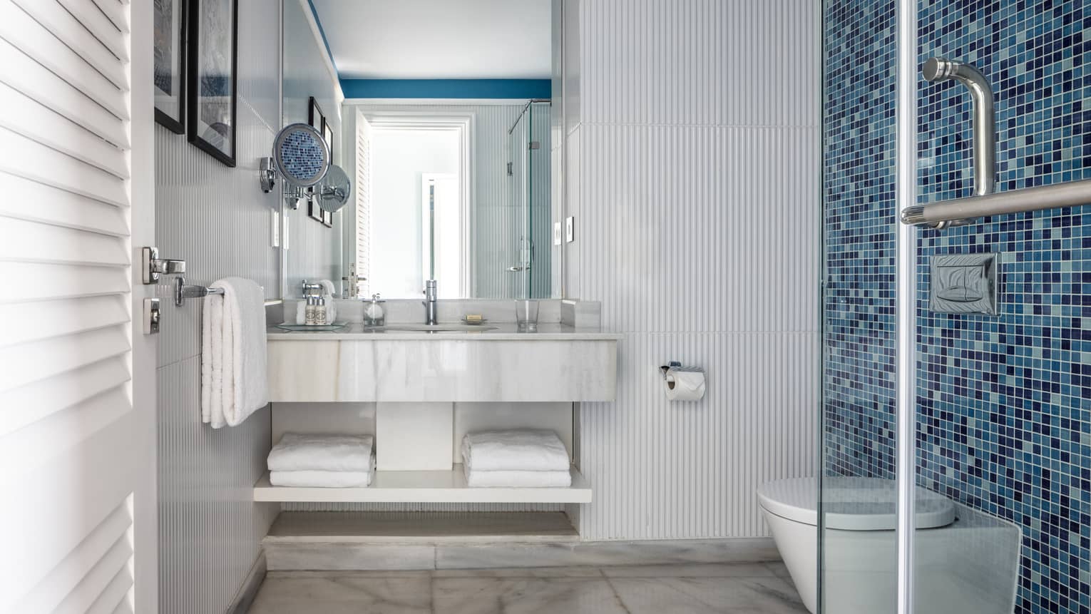 Suite bathroom with walk in shower, blue tiled wall, double vanity, mirror