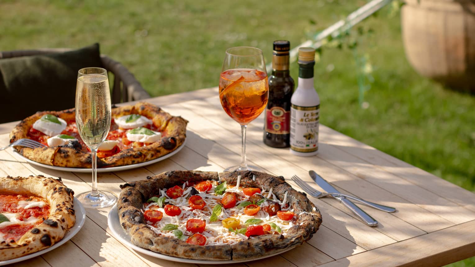 Homemade pizzas set on outdoor teak dining table