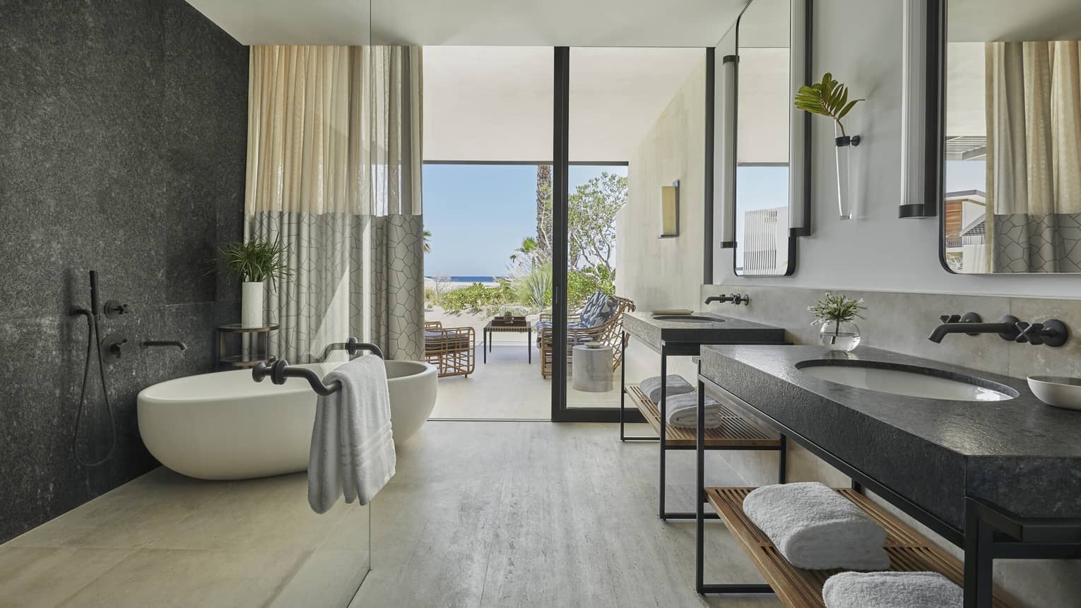 A bathroom with two sinks, a bathrub, and large windows.