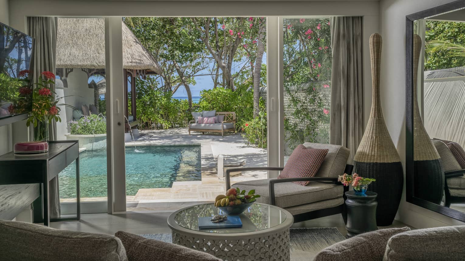 Living room opening to pool deck, with beach in the distance