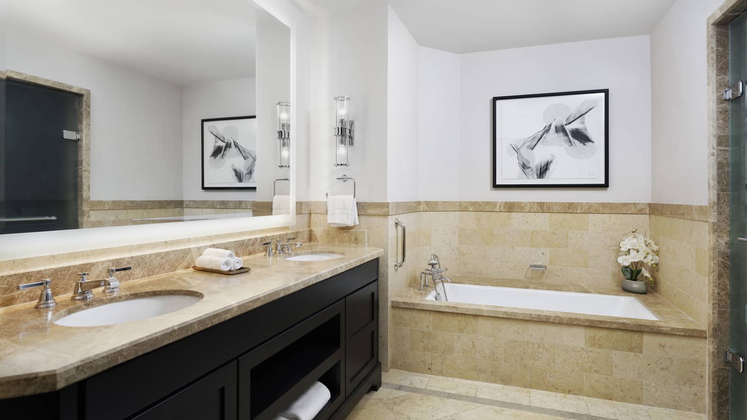 Guest bathroom with double sink and vanity, in-ground tub, tiled wall at chair rail, full-width mirror