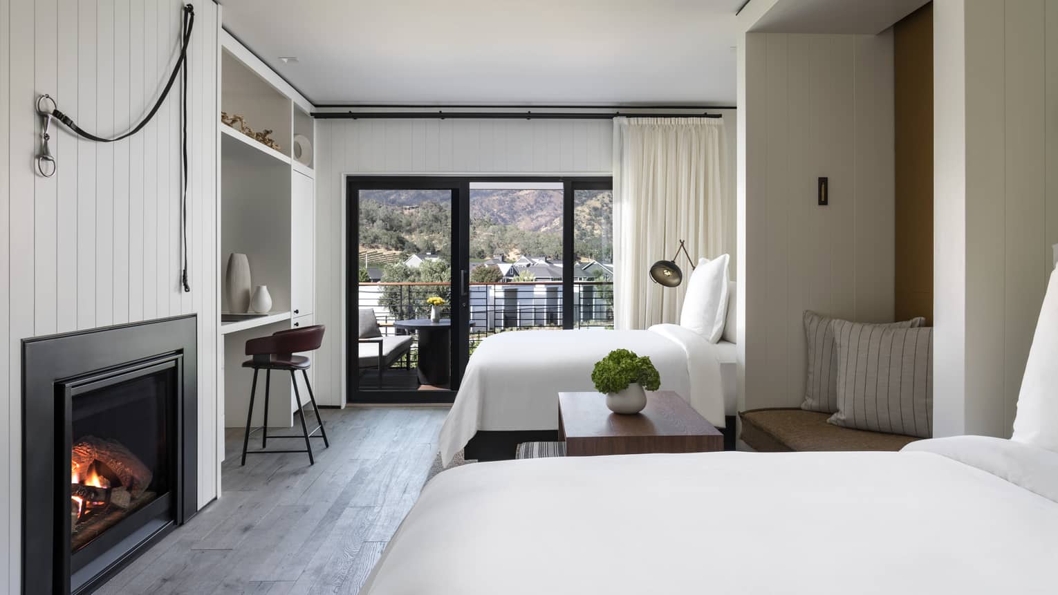 Luxury resort room with two beds, fireplace, mountain-view balcony, writing desk, seating nook and modern decor