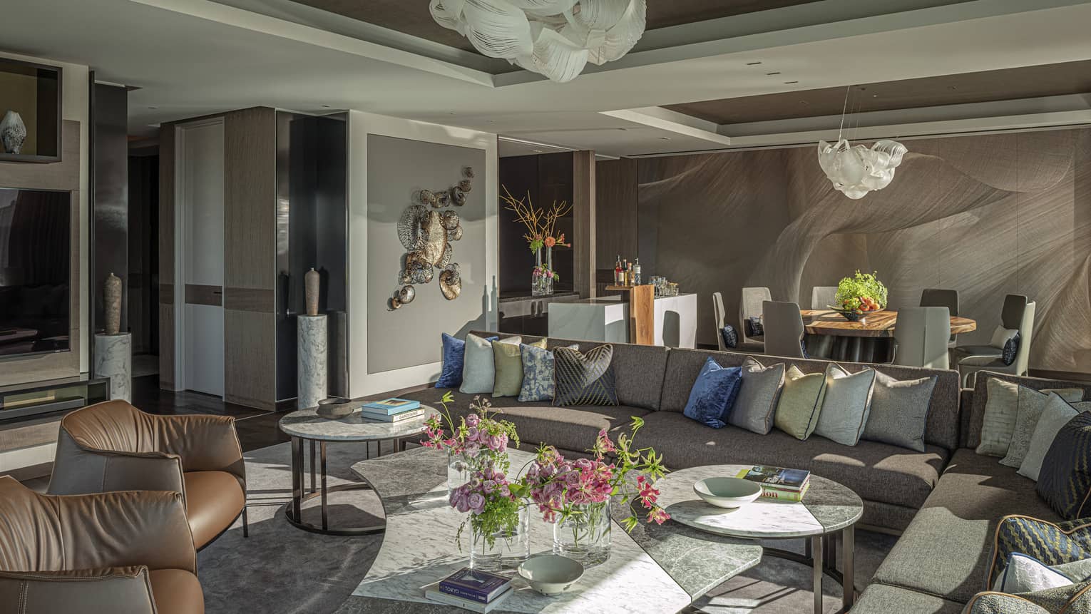 Elegant living room with large sectional sofa with many pillow, two leather chairs and dining table