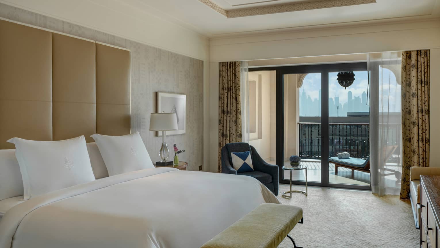Bedroom with king bed, white sheets, tan headboard, balcony