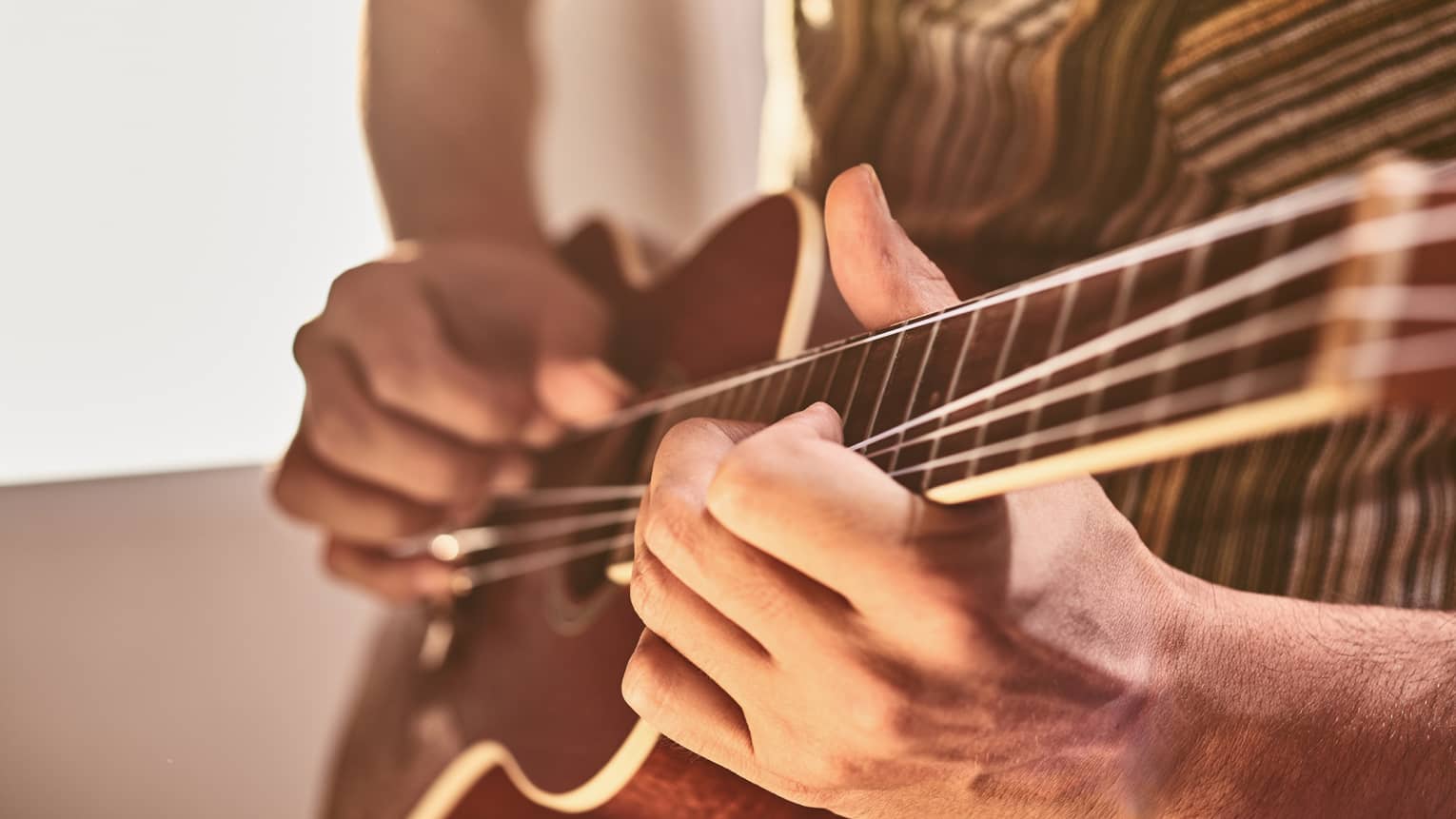 Close-up of hands playing ukulele stringed instrument