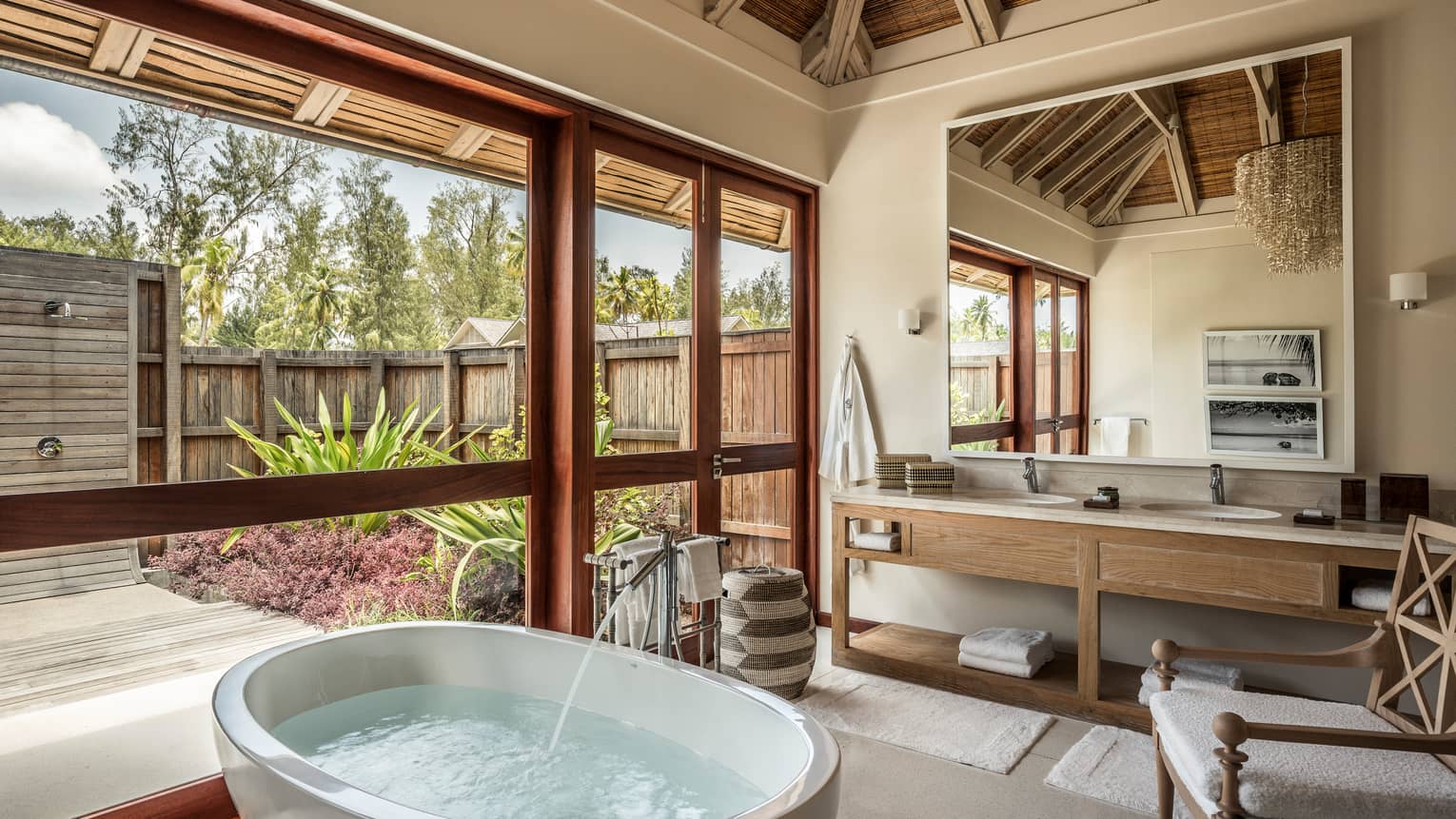 Water filling round soaking tub under window in bright bathroom