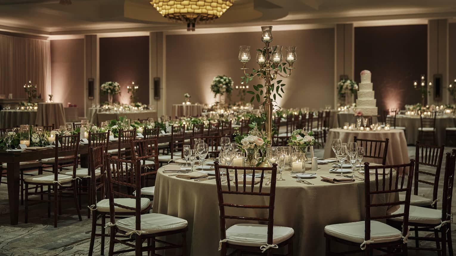 Long and circular tables are adorned with flowers and place-settings in preparation for a wedding party