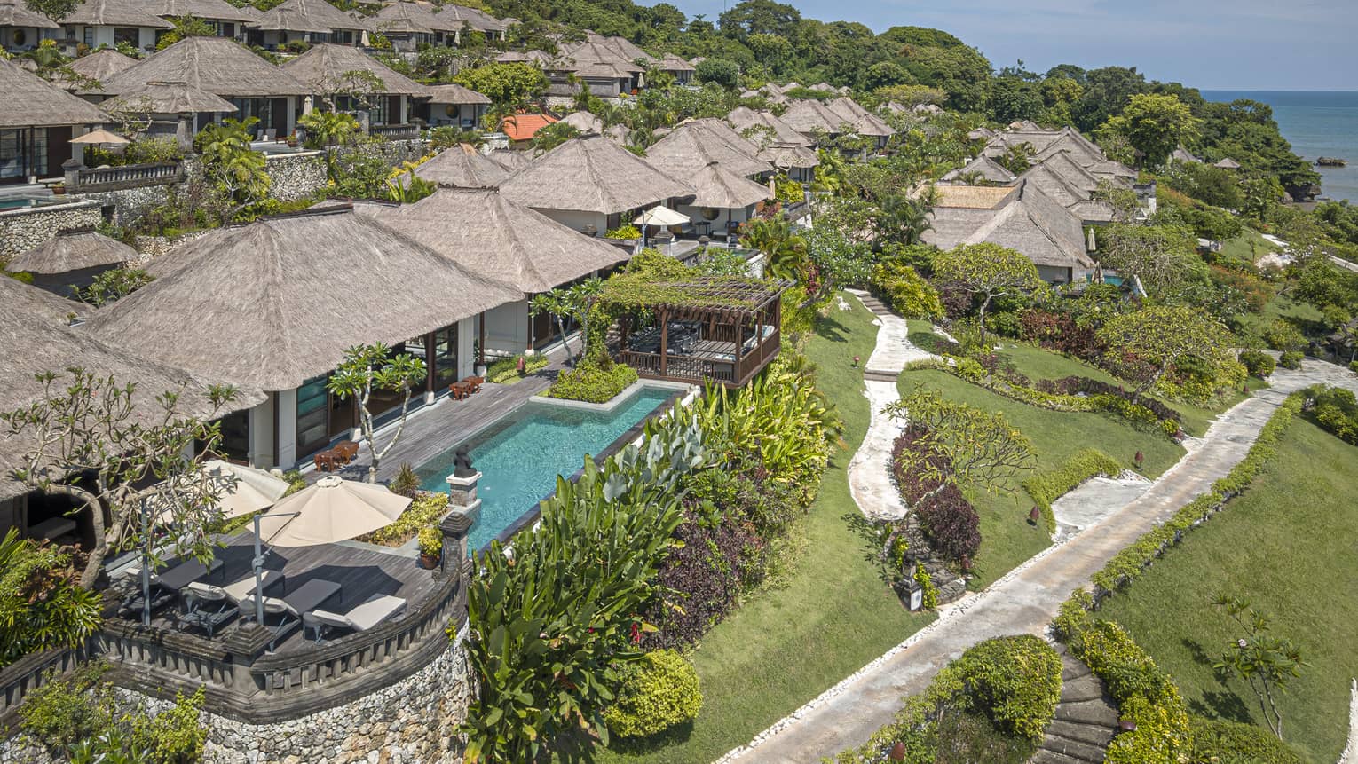 Aerial view of Royal Villa with pool, rolling green hills, ocean views