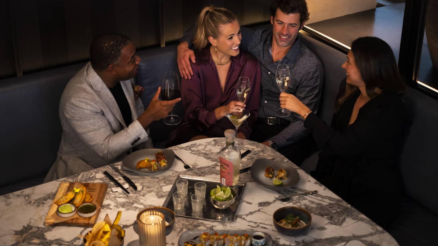 A group of people sitting at a booth in a dining outlet surrounded by food.