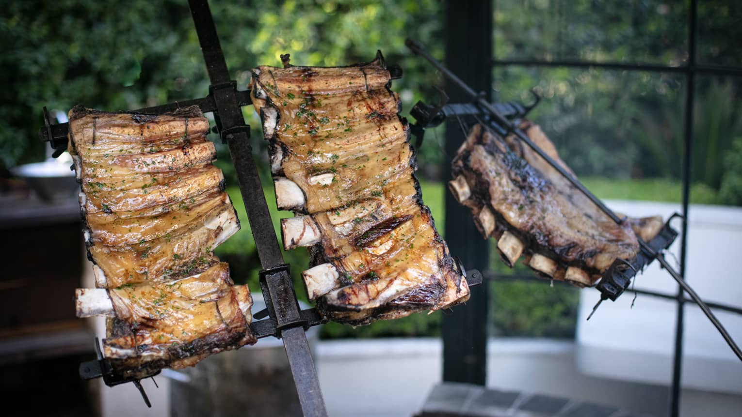 Several racks of ribs roasting over a fire.