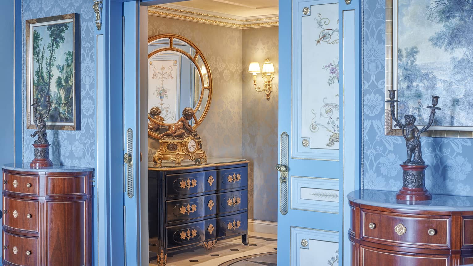 Presidential Suite entryway with cherry sideboards on either side of doorway, blue patterned wallpaper and wall art