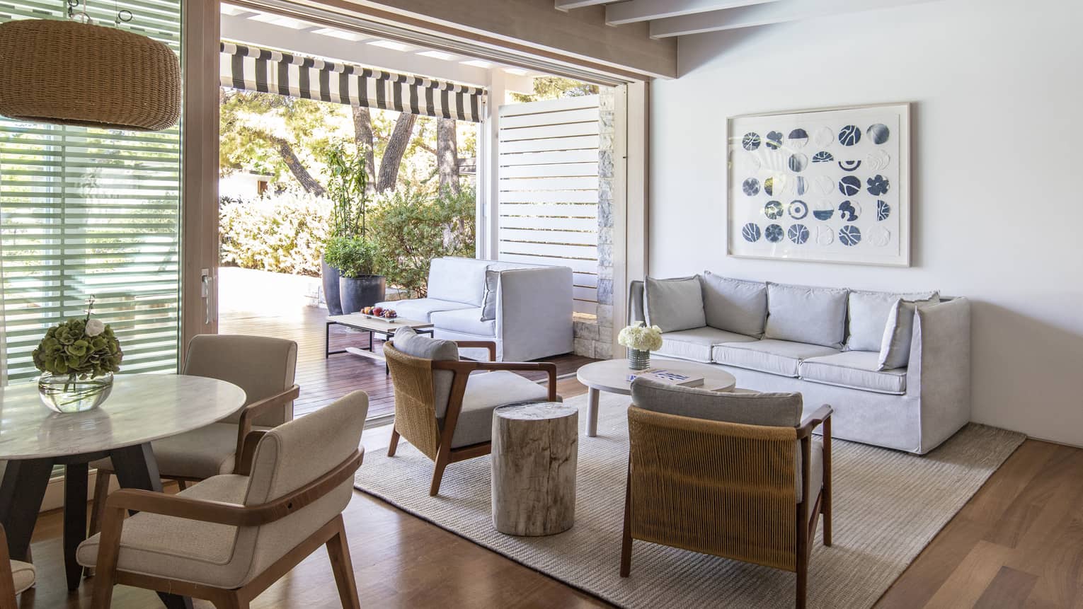 Living room with grey sofa, two chairs, dining table, walk-out terrace
