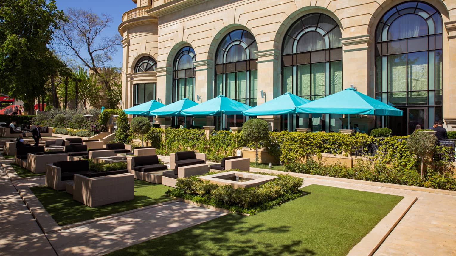 Eyvan Terrace dining area with shaded lounge and tables with aqua-blue umbrellas