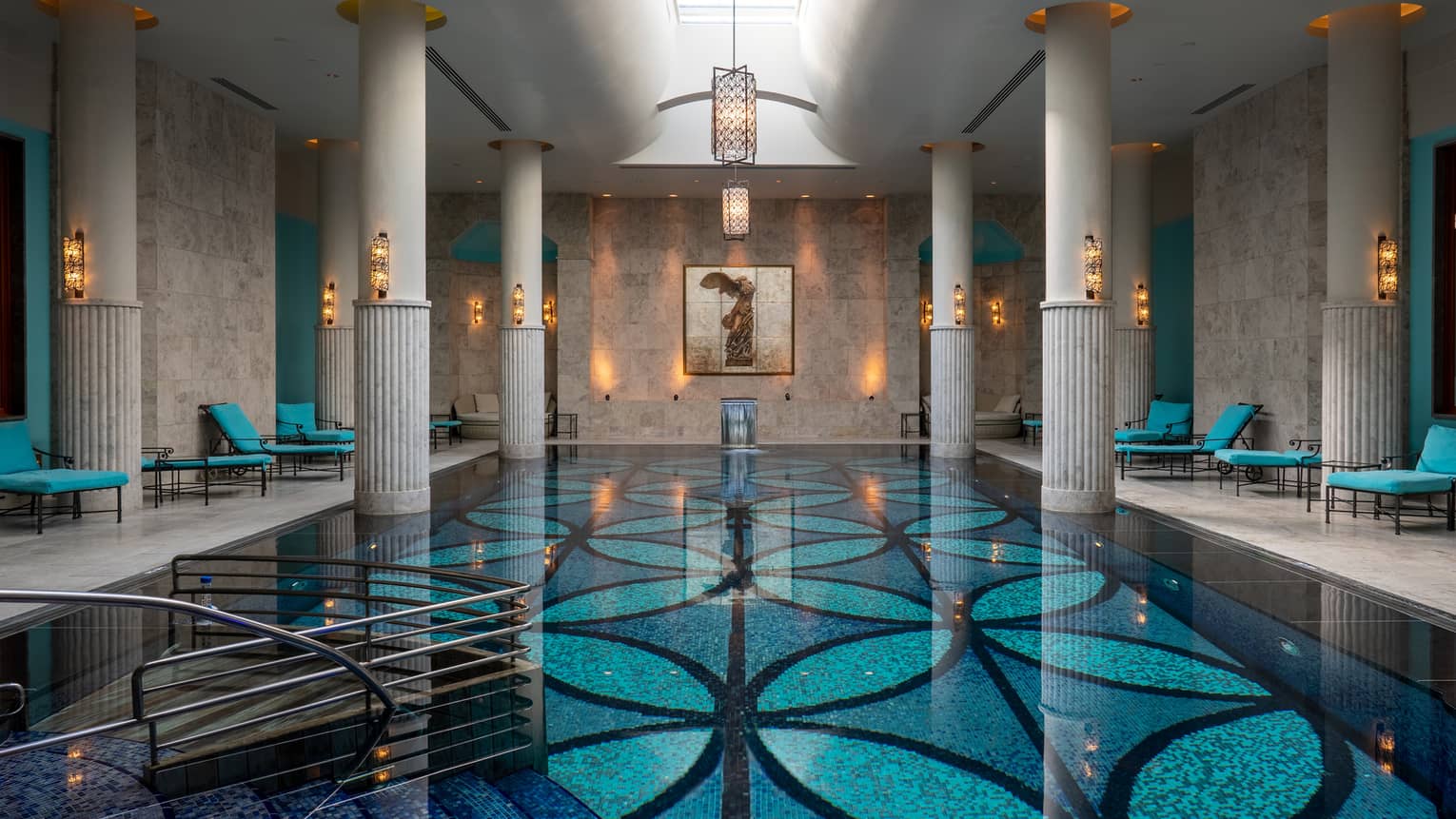 Indoor pool with blue-patterned floor, white up-lit columns and skylight