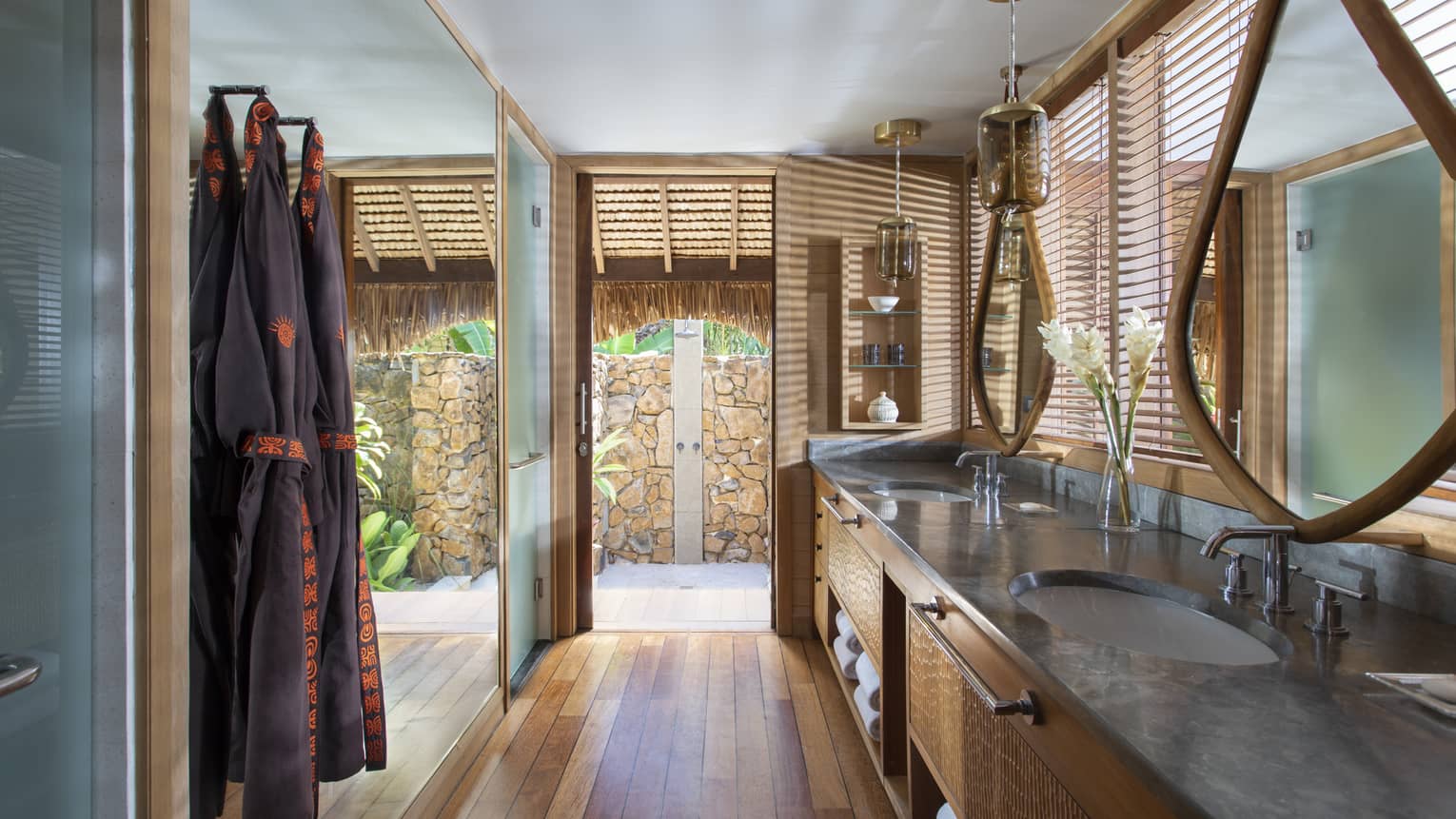 Double vanity sinks in an indoor-outdoor villa bathroom, with teak floors