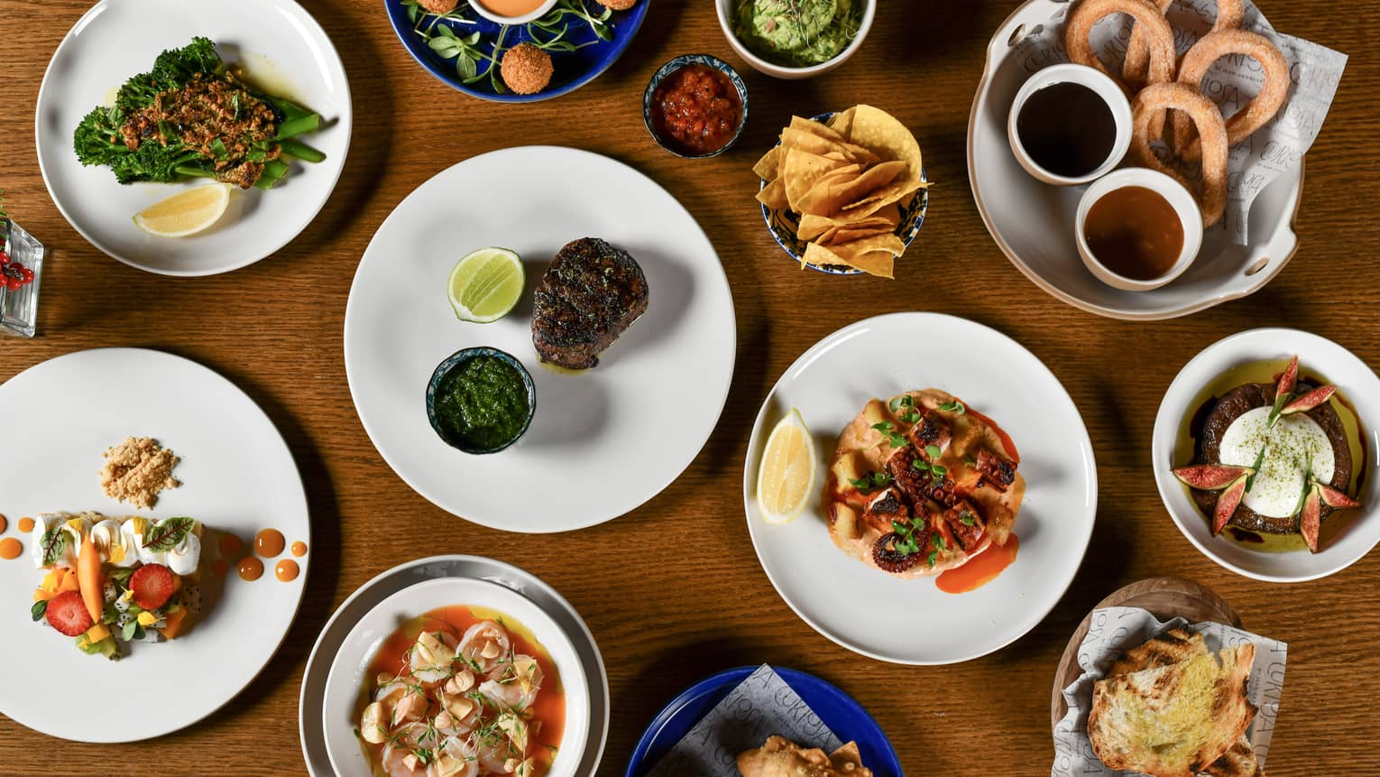 An overhead view of a wooden table filled a variety of dishes and bowls of food