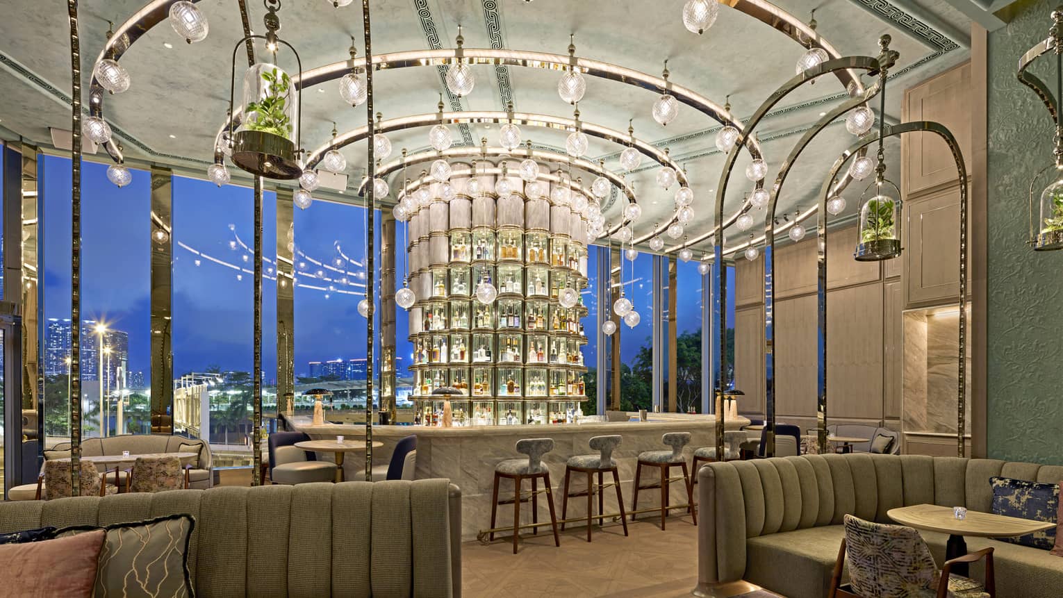 Bar area with cylindrical glass pillar behind bar holding liquor bottles, circular track lighting