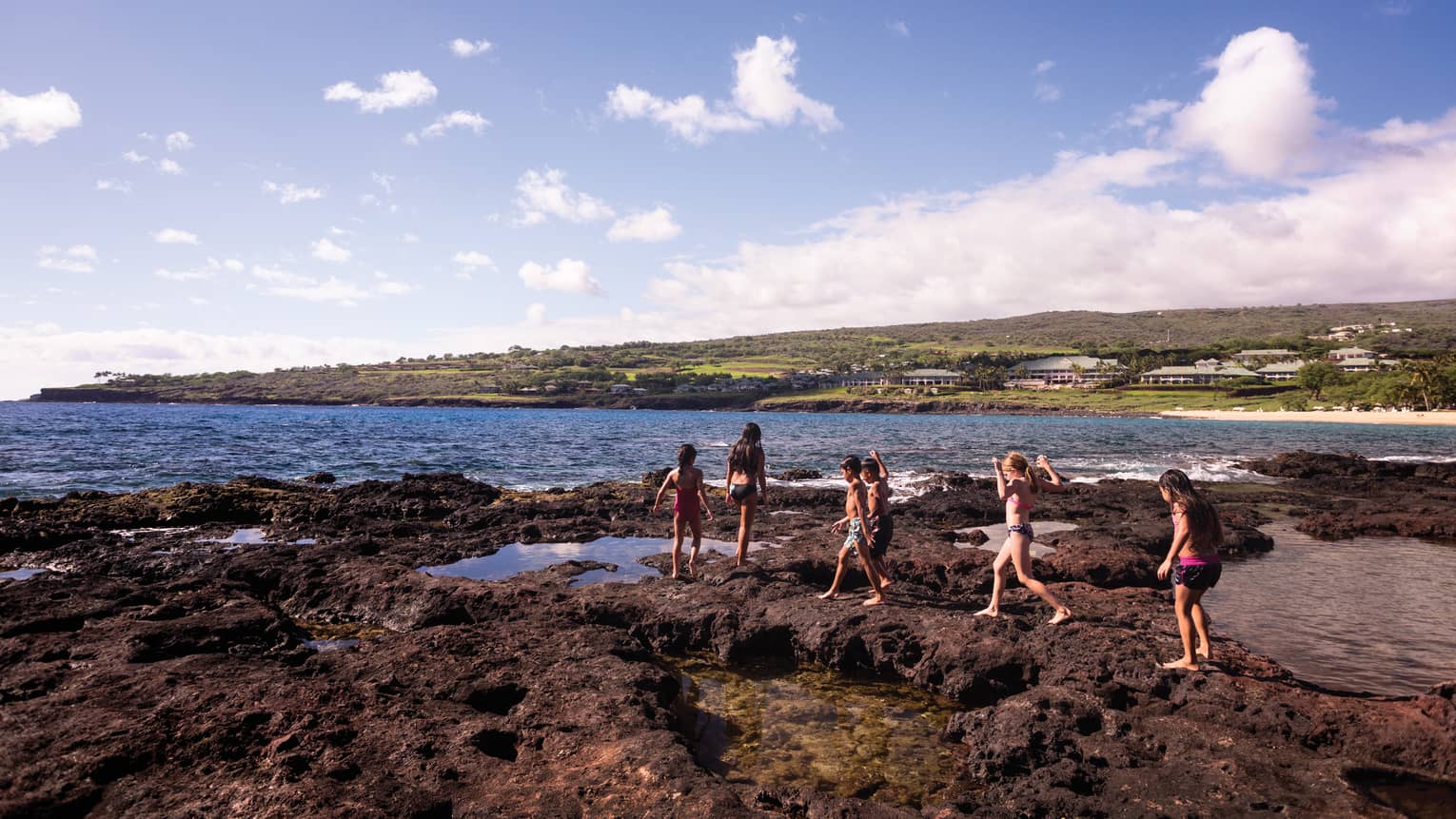 Kids walk on lava-rock beach in Lanai, Hawaii
