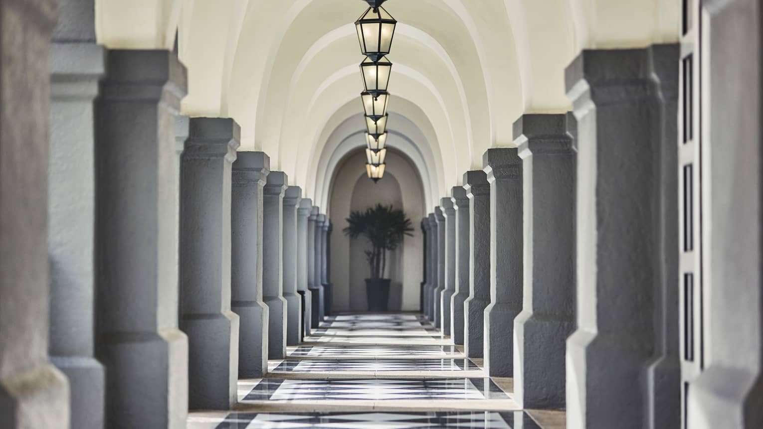 Stone pillars, lanterns down long, sunny outdoor hallway