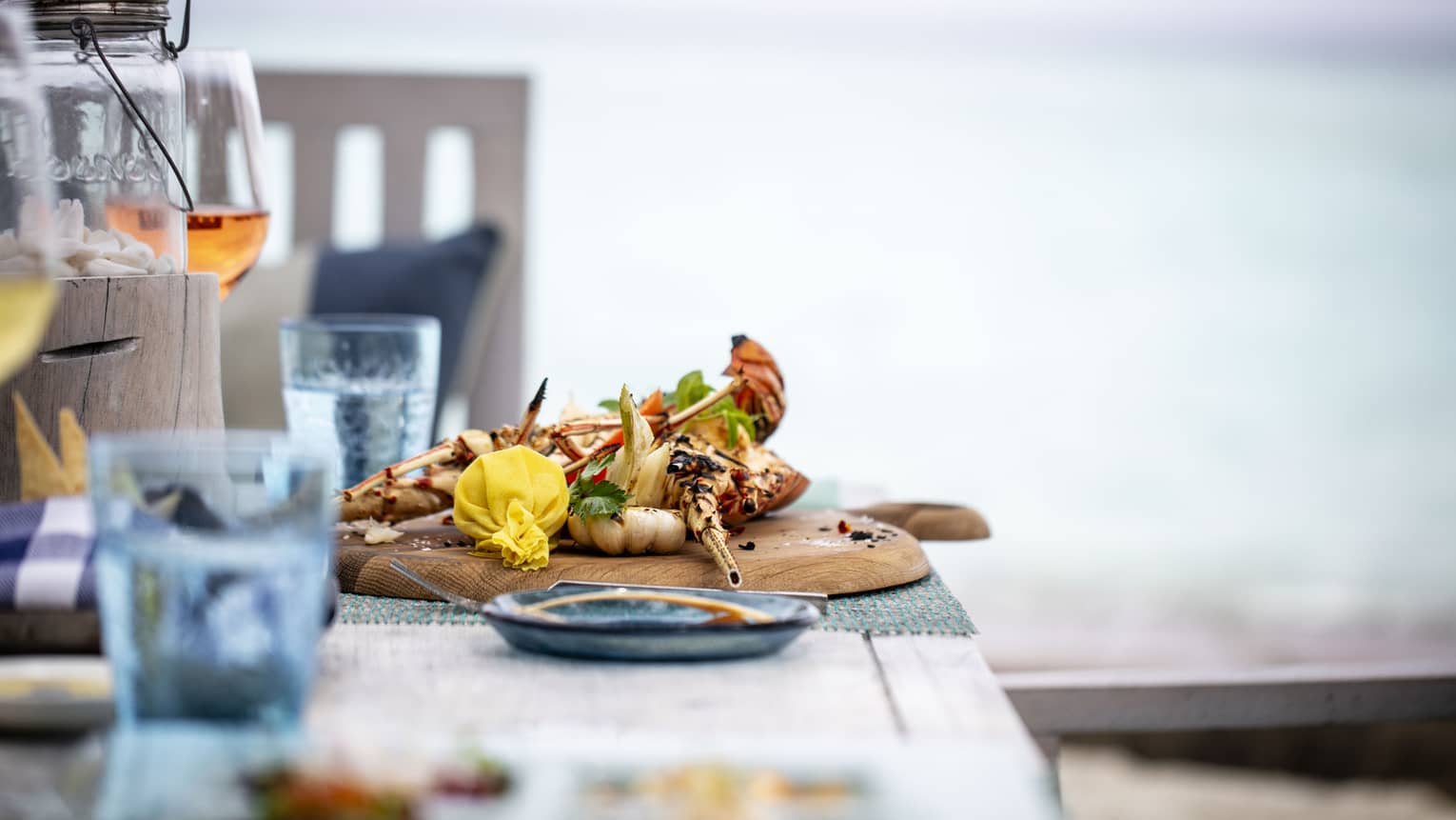 A tastefully set table with a glass of rose and a chicken dish overlooking the ocean at Fuego Grill