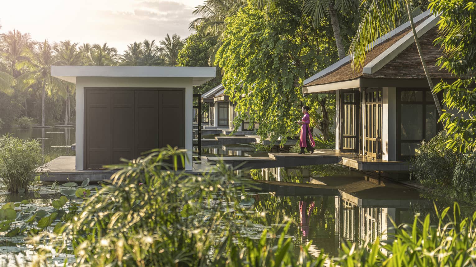 Woman walks across footbridge to a Spa treatment villa