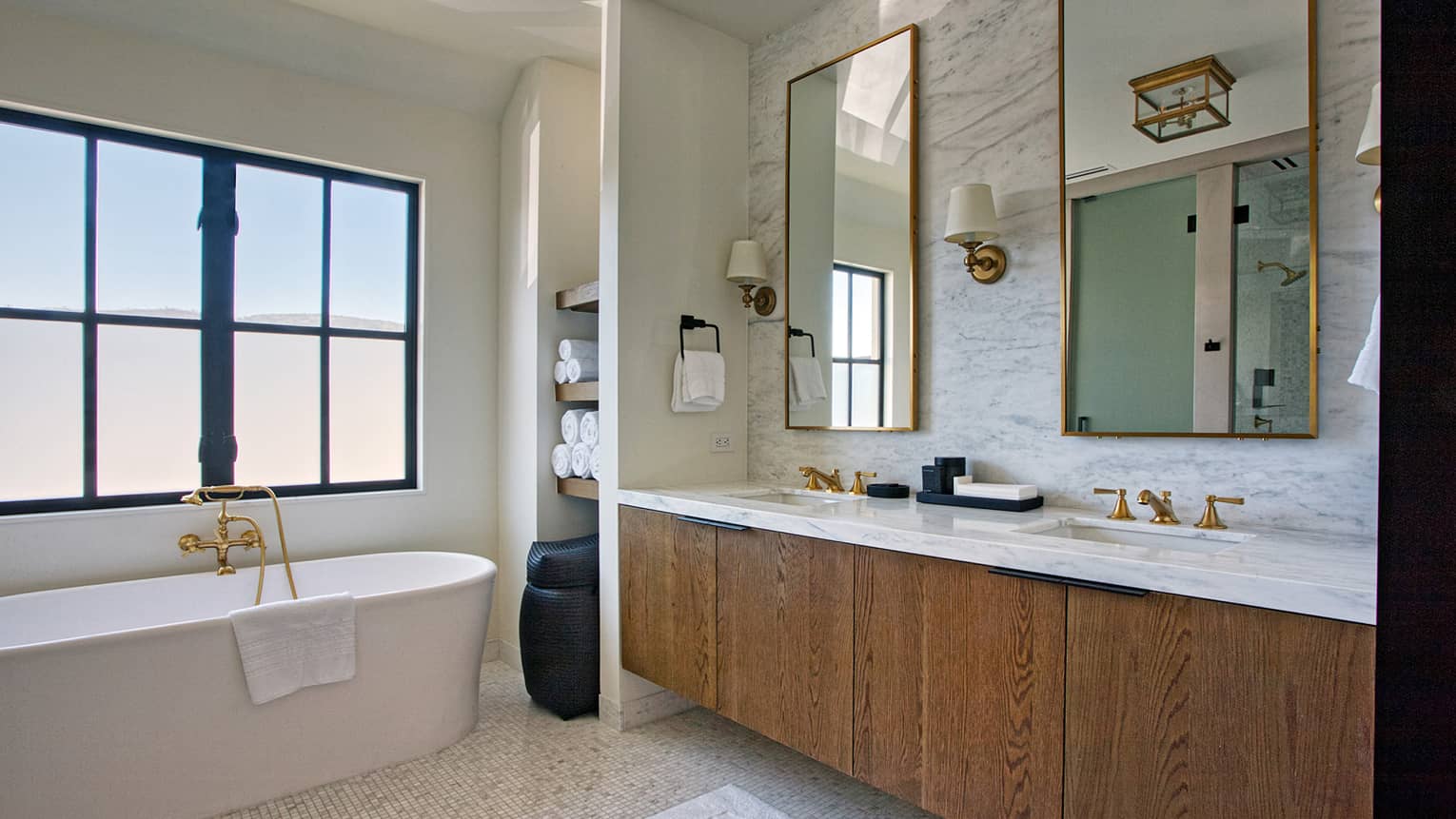 Bathroom with wood and marble double vanity, standalone tub and window