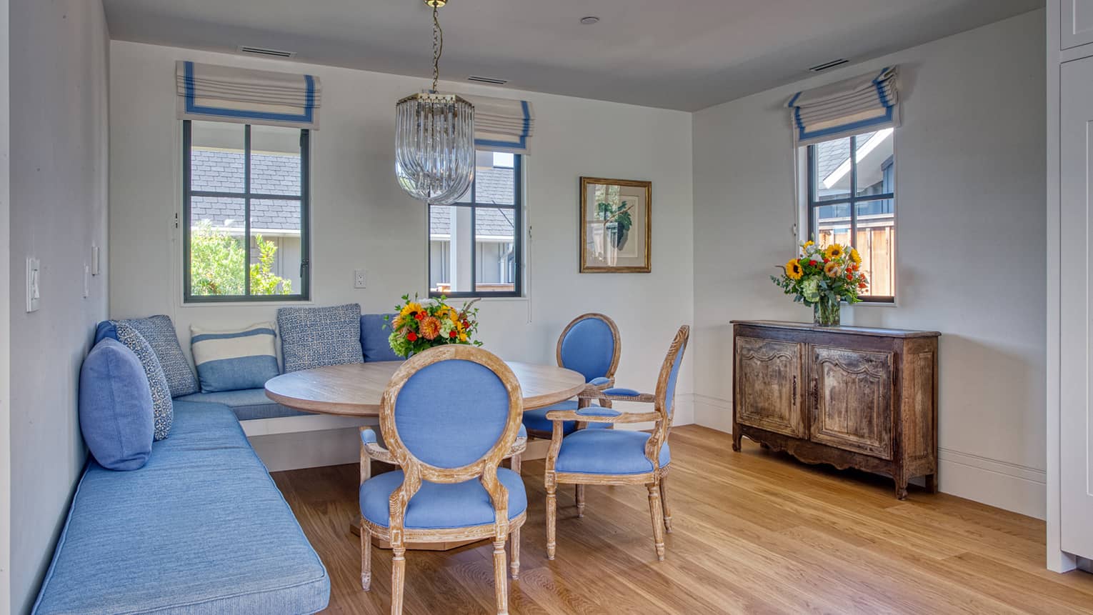 Dining room with round table, built-in blue-cushioned benches and three blue chairs