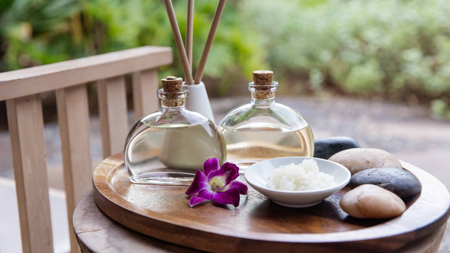 Spa oils and hot stones on wooden platter