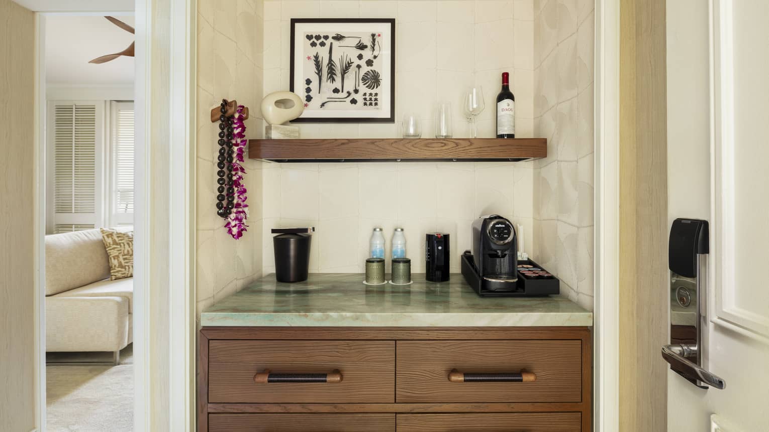 A wet bar within a contemporary resort room, featuring a coffee machine, water, ice bucket and a bottle of wine