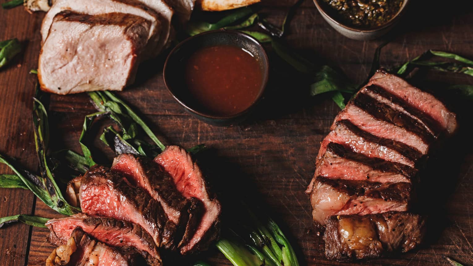A aerial view of the La Hiki Steak over green onions with a red sauce on the side