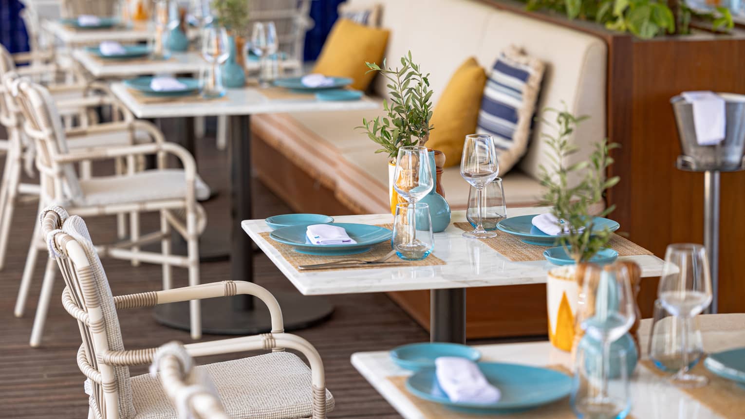 Banquette seating with colourful pillows along tables on restaurant terrace